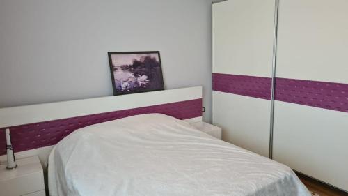 - une chambre avec un lit blanc et des murs violets dans l'établissement Flavio Apartament Comfort, à Pogradec