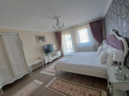 a bedroom with a white bed and a tv at Conacul Poetilor in Gura Rîului