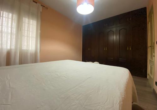 a bedroom with a white bed and a black door at Apartamento Calle Galaroza in Huelva