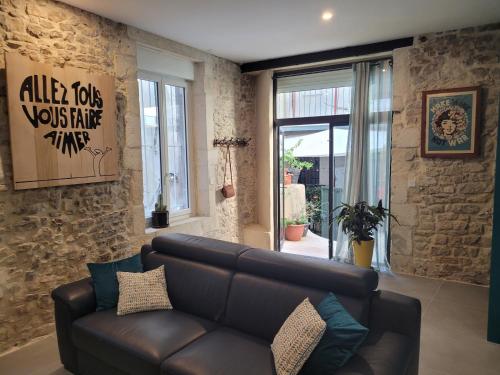 - un salon avec un canapé en cuir et un mur en pierre dans l'établissement L'atypique des arènes, à Nîmes