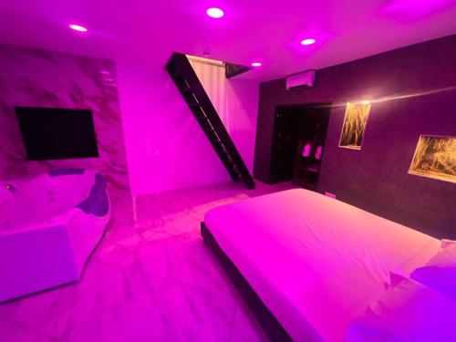 Habitación de color rosa con cama y TV en Maison Appartement Triplex avec jacuzzi et sauna en Saint-Étienne