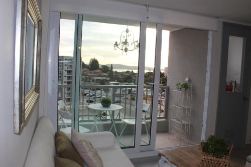 a living room with a couch and a balcony with a table at Lindo departamento vista al mar in Coquimbo