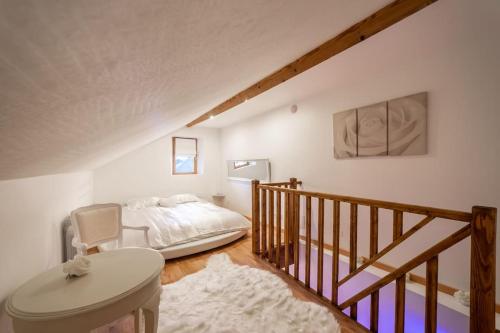 a bedroom with a bed and a staircase with a chair at L'AppartOsé, triplex jacuzzi, love room Aix-les-Bains in Tresserves