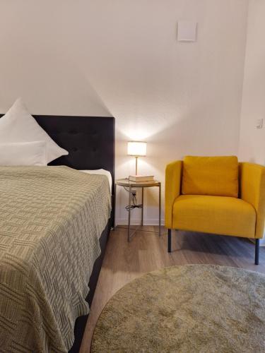 sypialnia z łóżkiem i żółtym krzesłem w obiekcie Stadt-Appartement am Nordpark w mieście Bielefeld