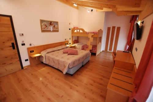 a bedroom with a bed and a bunk bed with a ladder at Hotel Chalet Alaska in Pozza di Fassa