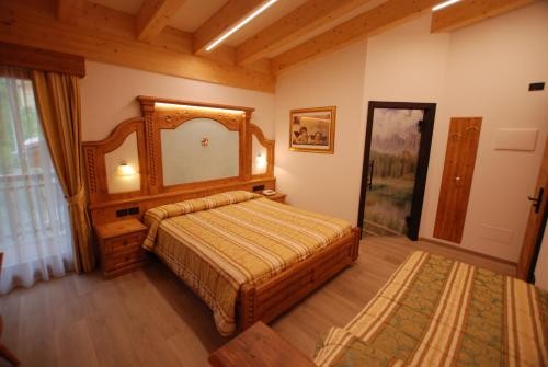 a bedroom with a bed and a large mirror at Hotel Chalet Alaska in Pozza di Fassa