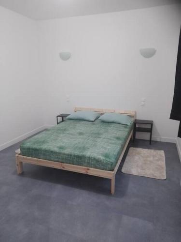 - un lit avec une couverture verte et des oreillers dans l'établissement appartement 2 T2 neuf et élégant proche zénith, à Pérignat-lès-Sarliève