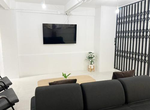 a living room with a couch and a tv on a wall at River Home Bangkok in Bangkok