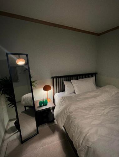 a bedroom with a bed and a mirror and a lamp at Jnineguesthouse in Seoul