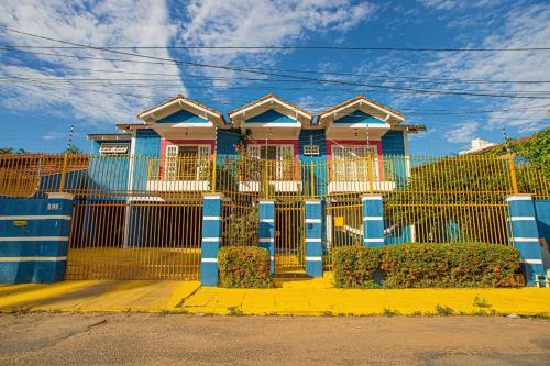 a house with a blue fence in front of it at Happiness House Hospedagem in Cuiabá