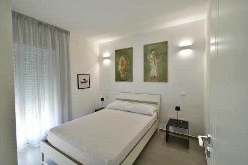 um quarto branco com uma cama e duas pinturas na parede em Palazzo Mosillo em Sperlonga