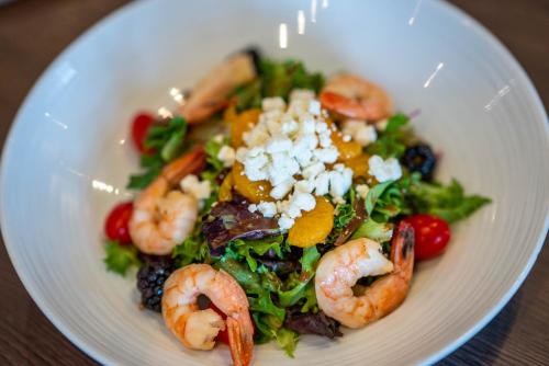 a white plate with a salad with shrimp and vegetables at Lake Louise Inn in Lake Louise