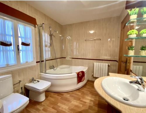 a bathroom with a tub and a toilet and a sink at Casa Outeiro in Betanzos