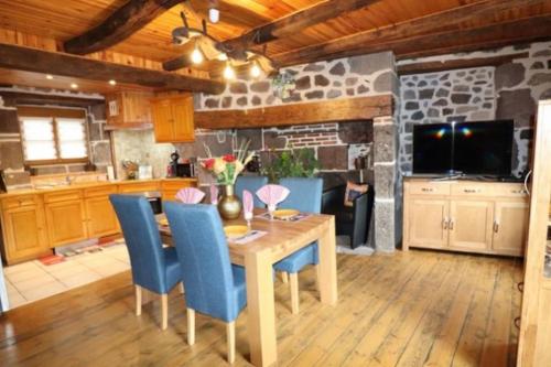 een keuken met een houten tafel en blauwe stoelen bij AUX VALLONS MELODIEUX in Thiézac