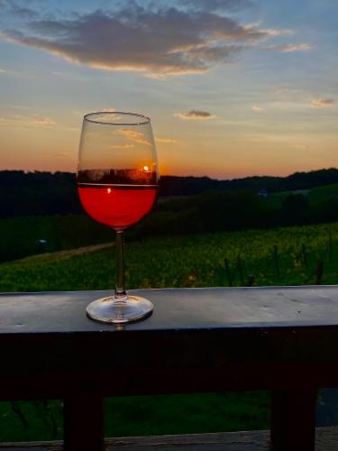 a glass of wine sitting on a table with the sunset at Pension Rucksackpeter in Hohenbrugg an der Raab