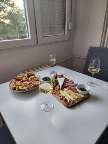 een tafel met twee glazen wijn en een dienblad met eten bij Stan na dan Nova Varoš in Banja Luka