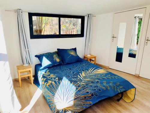 a bedroom with a bed with blue sheets and a window at Le cabanon de Manon - Marseille in Marseille