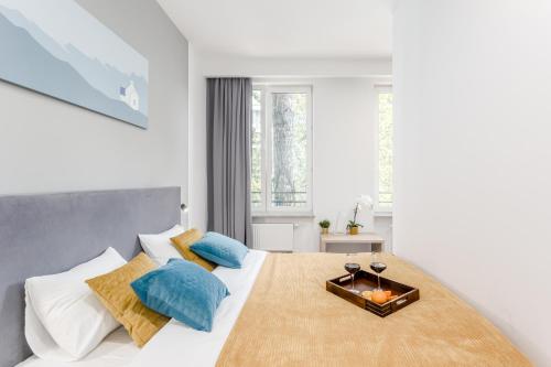 a white bedroom with a large bed with blue pillows at Warsaw City Apartments EXPO in Warsaw