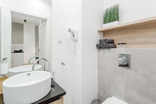uma casa de banho branca com um lavatório e um espelho em Warsaw City Apartments EXPO em Varsóvia