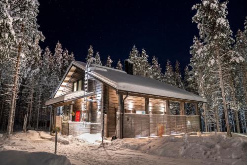 una cabaña de madera en la nieve por la noche en Charming log house - Lumous B - Pyhätunturi - Finland en Pyhätunturi