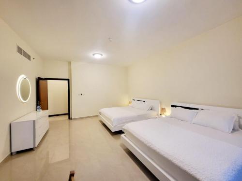 a hotel room with two beds and a mirror at Beachfront Holiday Homes in Ajman 