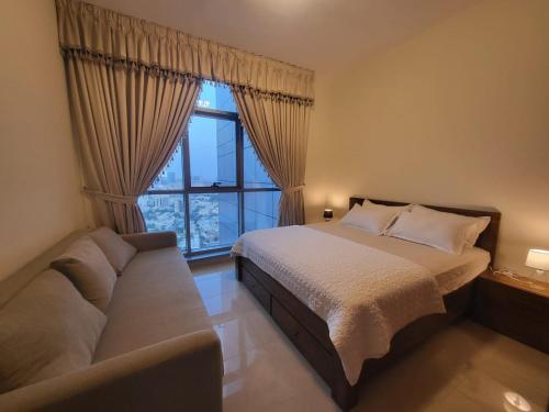 a bedroom with a bed and a couch and a window at Beachfront Holiday Homes in Ajman 