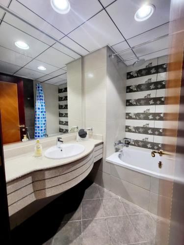 a bathroom with a sink and a tub and a mirror at Beachfront Holiday Homes in Ajman 
