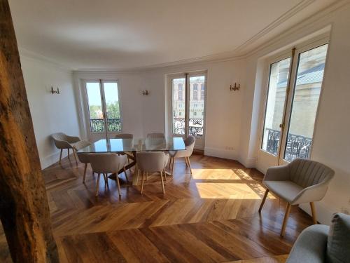 une salle à manger avec une table, des chaises et des fenêtres dans l'établissement Face château St Germain en Laye, appartement 4 à 6 personnes, 23 min de Paris Champs-Elysées, à Saint-Germain-en-Laye