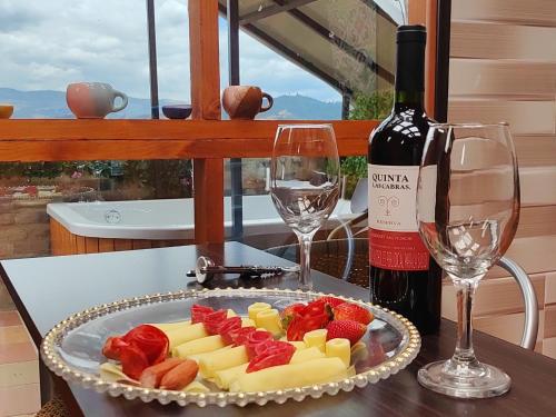 un plato de queso y fruta en una mesa con una botella de vino en Glamping VILLA - Nueva en Paipa, en Paipa