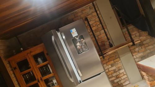 a kitchen with a stainless steel refrigerator and a brick wall at Casa da Pedra Serrinha in Resende