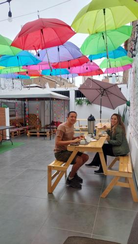 2 personnes assises sur une table de pique-nique sous des parasols dans l'établissement JUMANA, à Nazca