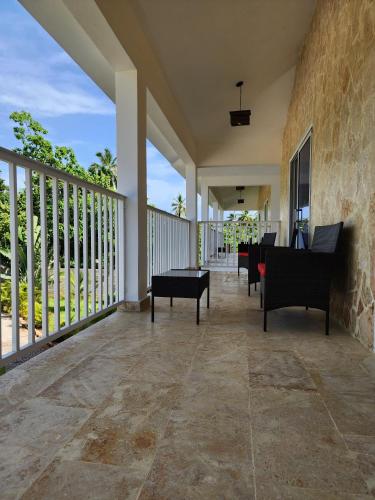 a porch with chairs and tables on a balcony at Bella Villa Roomy apartment at 5 min walk to the beach in Las Galeras