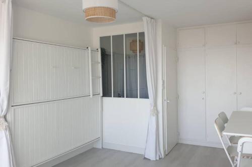 a white kitchen with white cabinets and a table and a window at Le Front de Mer, superbe vue mer in Saint-Jean-de-Monts
