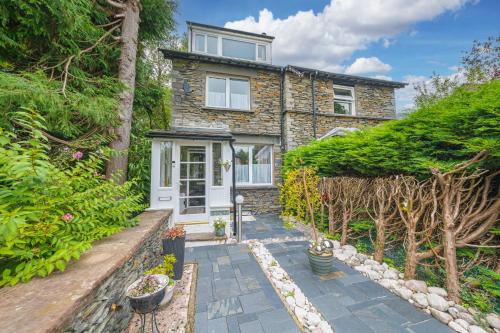 a stone house with a pathway leading to the front door at Sunny Brae, dog friendly Windermere Cottage in Windermere