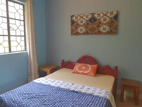 a bedroom with a bed with an orange pillow on it at Sinana country Home-Backpackers Stay in Kibongoto