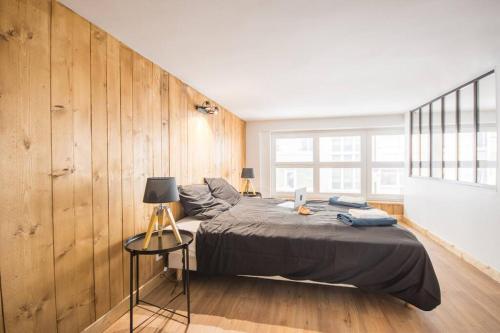 ein Schlafzimmer mit einem großen Bett und einer Holzwand in der Unterkunft L'appar-T, esprit industriel à 2 pas de l'eau ! in Le Havre