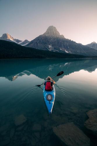 a person is paddling a kayak on a lake at Lake Louise Inn in Lake Louise