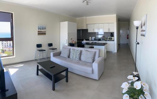 sala de estar con sofá blanco y cocina en Appartement avec vue imprenable sur l'océan en Praia da Lourinhã