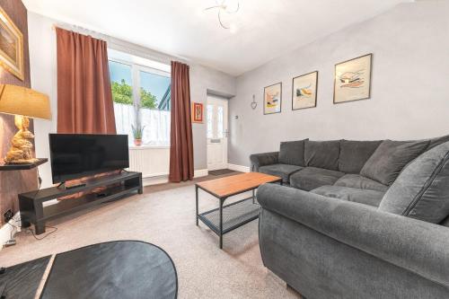a living room with a gray couch and a television at Sunny Brae, dog friendly Windermere Cottage in Windermere