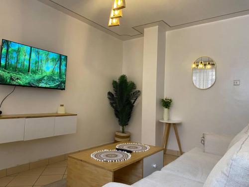 a living room with a couch and a tv on the wall at The Manna Condo - South B in Nairobi
