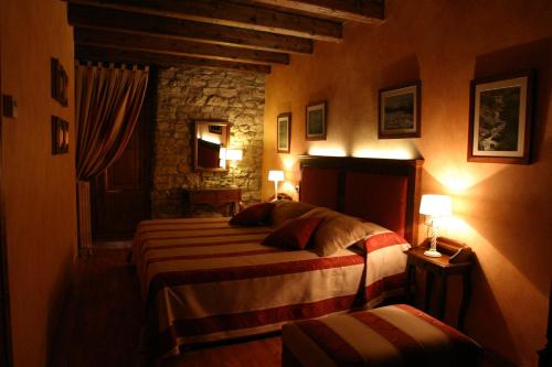 a bedroom with two beds and a stone wall at Casa rural Daudén in Cantavieja