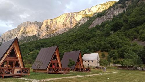 a group of cottages in front of a mountain at Etno apartmani Komarnica in Šavnik