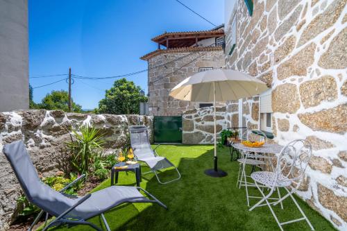 a patio with a table and chairs and an umbrella at Casinhas do Miga in Santa Comba Dão