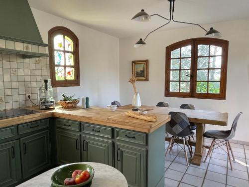 a kitchen with green cabinets and a table with a bowl of fruit at Villa Grand Cèdre in Marseille