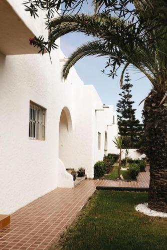 a white building with a palm tree next to it at Villa Vue sur la Méditerranée in Cabo Negro