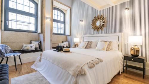 a bedroom with a large white bed and a mirror at Downtown PortoEdition in Porto