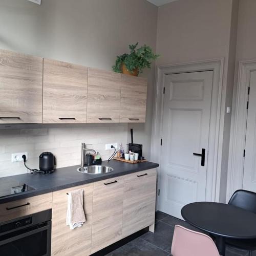a kitchen with a sink and a table and a door at Bij Ons In Harlingen in Harlingen