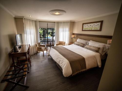 a hotel room with a large bed and a desk at Resort de montaña - La Comarca in Villa La Angostura