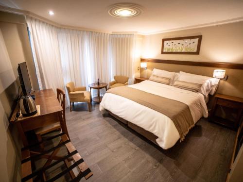 a hotel room with a large bed and a desk at Resort de montaña - La Comarca in Villa La Angostura