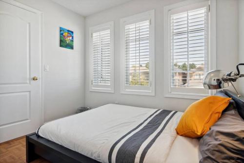 The cozy corner House in the Richmond Hill في ريتشموند هيل: غرفة نوم بسرير بجدران بيضاء ونوافذ